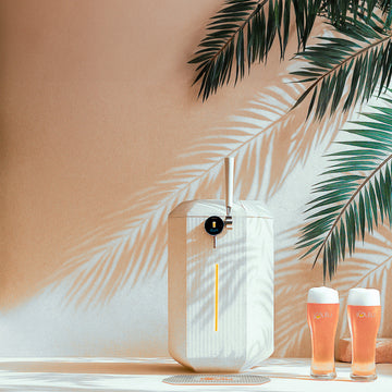 White iGulu F1 with two glasses of beer on a surface with palm leaves in the background